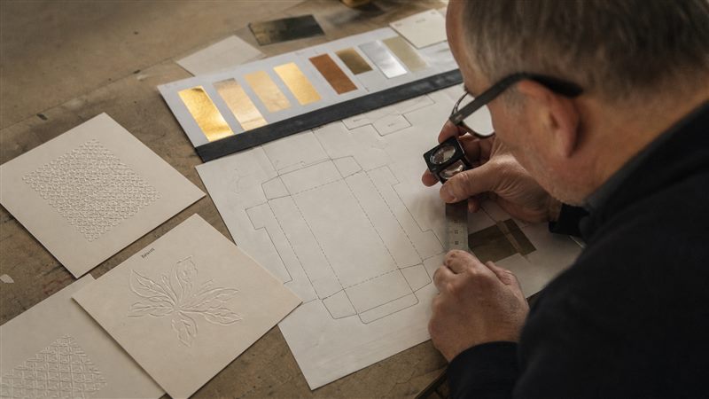 Packaging designer checking embossed and debossed samples with a loupe and ruler