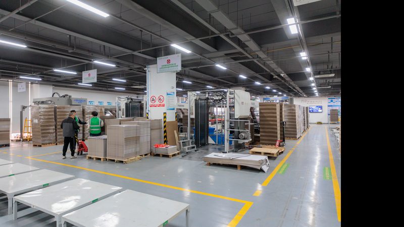 Modern corrugated packaging production line with stacked board sheets and pallets