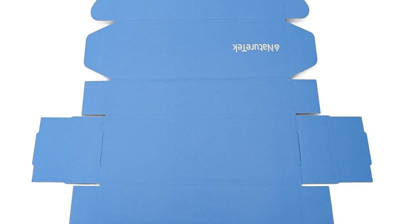 Blue flat carton dieline photographed in Colin packaging materials