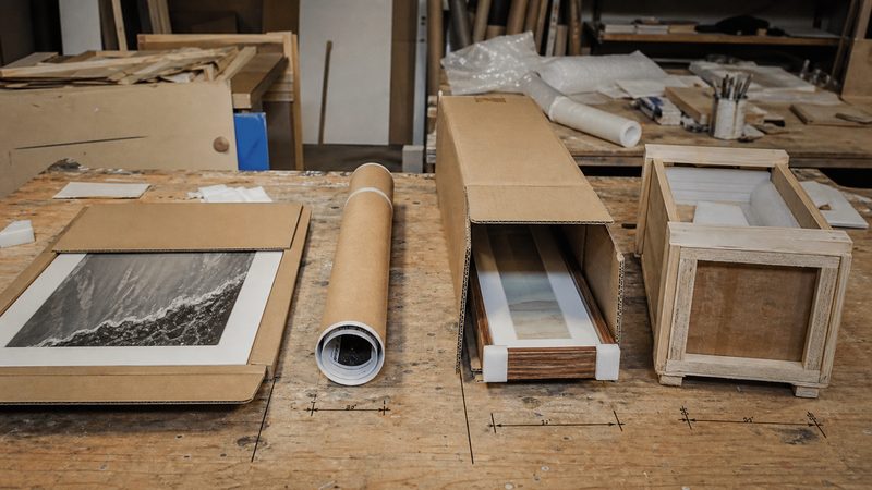 Rigid mailer, mailing tube, telescoping box and small crate arranged on an artwork packing table