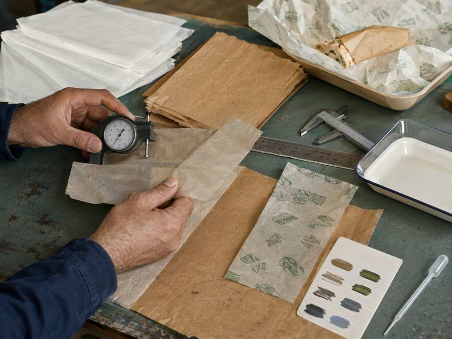 Supplier checking food paper thickness, coating and printed sample sheets with measuring tools