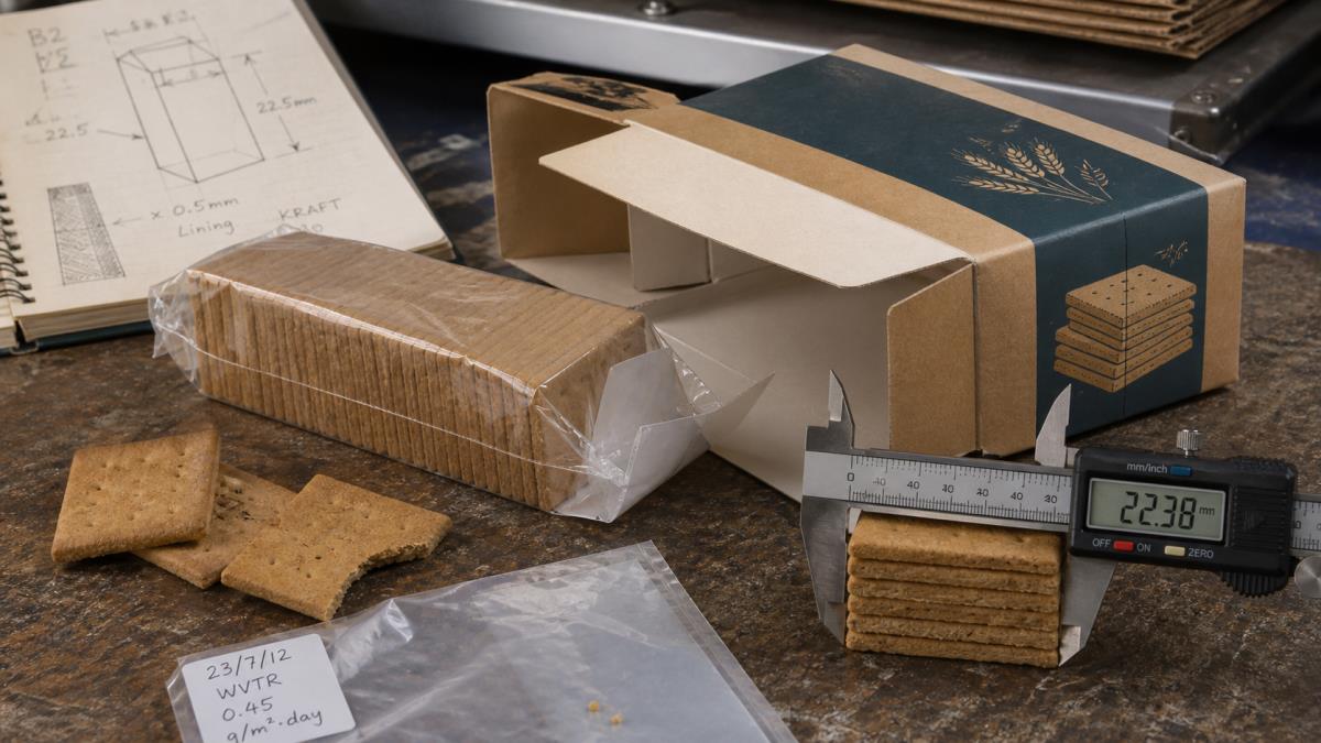 Caliper measuring graham cracker stack height beside an inner sleeve and paperboard carton