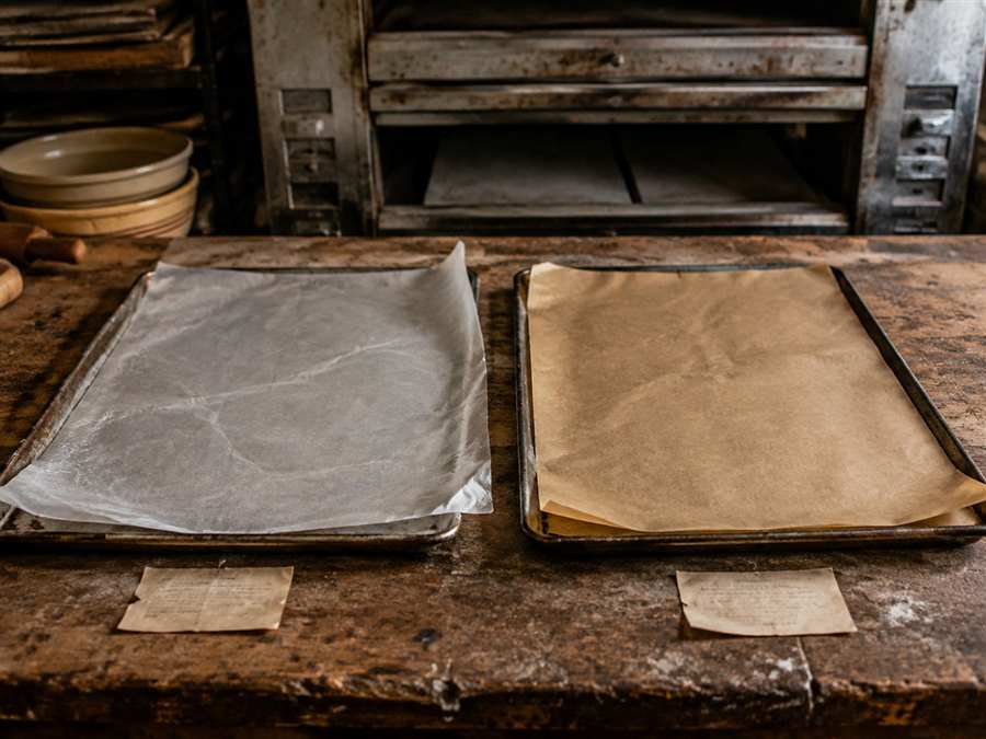 Separate wax paper and parchment paper sheets on baking trays in an old bakery